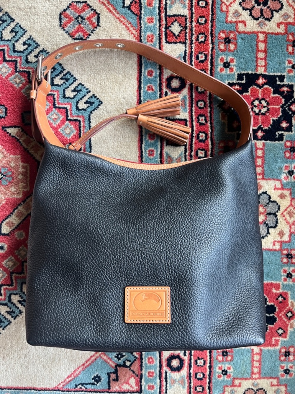Dooney & Bourke, Inc. Black pebble leather BoHo zipper bag with tassel.